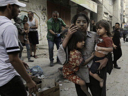 Una joven madre intenta llevar a resguardo a sus hijas durante los bombardeos de Israel en Gaza