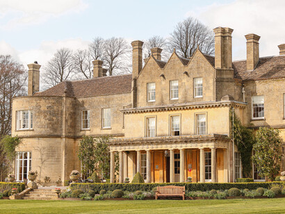 The grand entrance of Lucknam Park in Wiltshire, England, framed by lime and beech trees