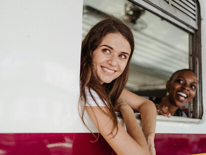 Women chatting on public transport, with one looking out the train window