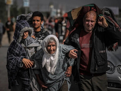 Palestinos ayudan a una anciana a caminar mientras huyen de las partes central y sur de la Franja de Gaza el 10 de noviembre de 2023
