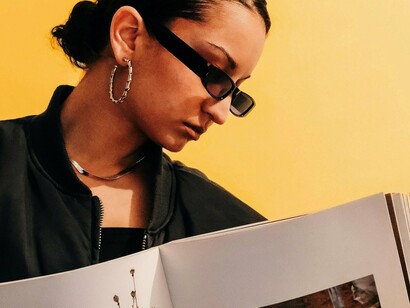 Mulher segura revista com propaganda estampada. Em um clipe, por exemplo, tudo é estrategicamente intencional, desde as cores escolhidas, os elementos da cena e a história contada. Tudo contribui para gerar uma conexão profunda com o inconsciente do público e despertar o desejo de comprar aquele produto