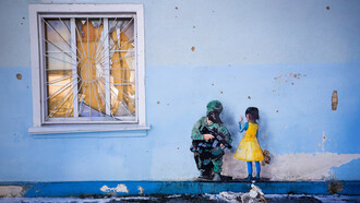 Grafiti en que una niña vestida con los colores de la bandera de Ucrania confronta a un soldado ruso