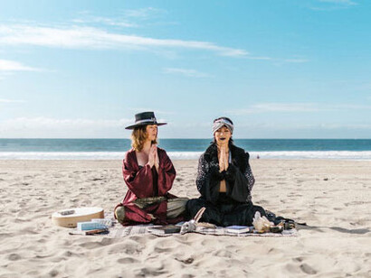 Dos mujeres armonizan con la energía del universo, sus movimientos en la playa reflejan una profunda conexión con las leyes que rigen la existencia