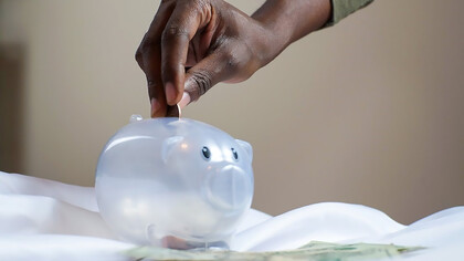 Person putting coins in piggy bank