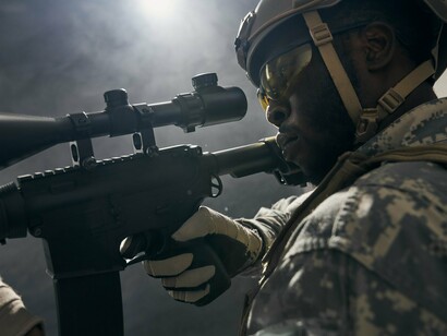 A heavily armed soldier coming out of a layer of smoke, reflecting the continuous armed confrontations across the continent
