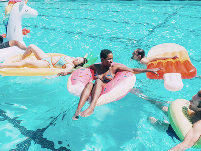 Friends floating on the swimming pool in their various inflatable pool toys