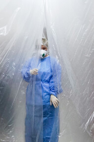 A doctor wearing a mask and lab coat stands behind a tarpaulin during the COVID-19 pandemic in Chernivtsi, Ukraine