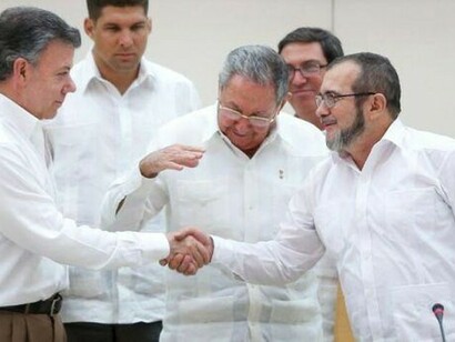 Santos, presidente de Colombia, y Tomichenko, líder de las FARC, se dan la mano delante de Raúl Castro (2016)