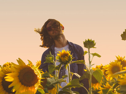 Muchacho parado entre girasoles, meciéndose con el viento