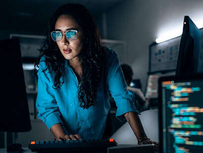 Female software developer coding late at night while interacting with an AI-powered assistan