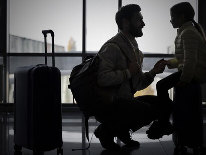 A father and his child await departure at the airport, beginning their journey abroad in search of new opportunities