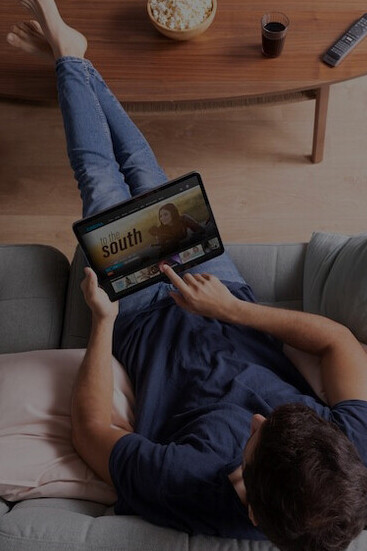 A man using his tablet to explore streaming options and pick the perfect movie