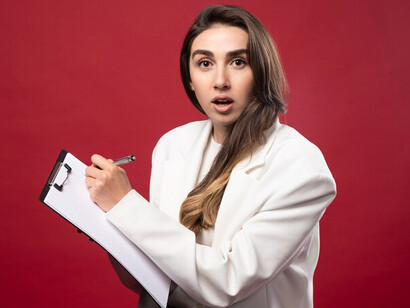 A female journalist sipping coffee while reviewing notes in her notebook, deep in thought