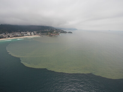 Foto do sobrevôo de 13/12/2016 onde se vê imensa mancha de esgoto, sedimentos e cianobactérias escorrendo das lagoas para a praia da Barra da Tijuca