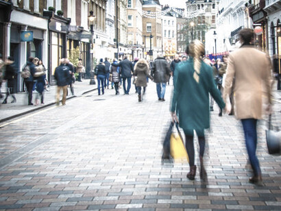 A lively scene of people walking on the UK’s High Street shopping street