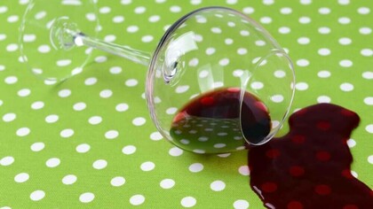 A glass of wine spilt on a brand new green and white polka dotted tablecloth
