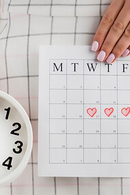 A woman holding a clock and calendar, symbolizing the importance of tracking menstrual health and cycle regularity