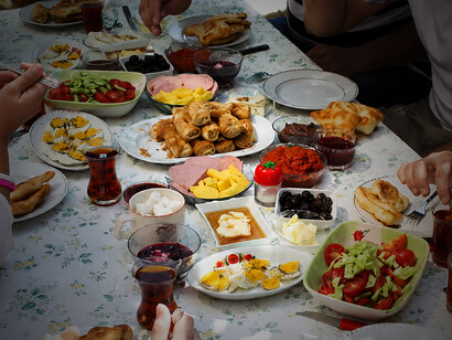 A Turkish family enjoys a traditional breakfast together, sharing a generous spread of classic dishes