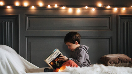 Pequeño niño observando atentamente un libro antes de acostarse