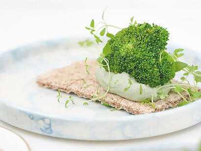 A selection of vibrant green vegetables meticulously presented on a clean, white ceramic plate