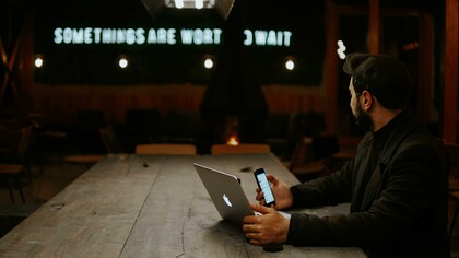 Man sitting at a table with a phone and laptop