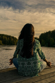 Mujer practicando yoga junto a un lago