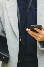 Mulher executiva utiliza o celular para trabalhar enquanto anda na rua