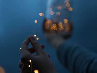 A person holds a glass of wine in a sparkly setting