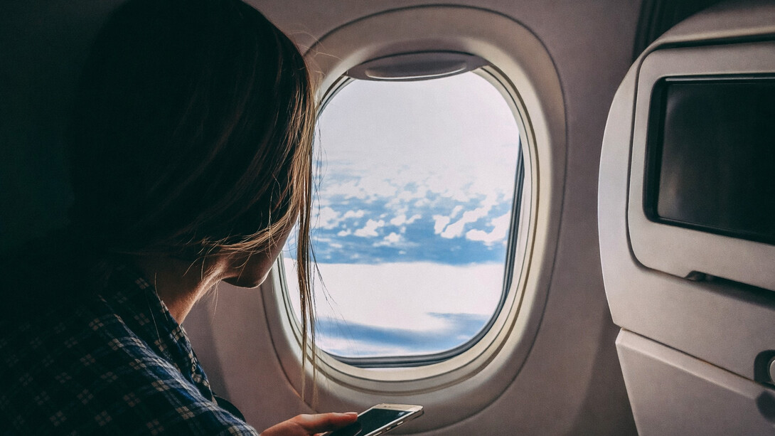 Person holding a smartphone while traveling on an airplane