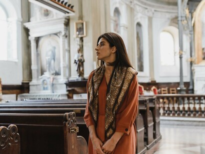A woman reflecting in the stillness of the church, representing the grace of God that invites every wandering heart back home
