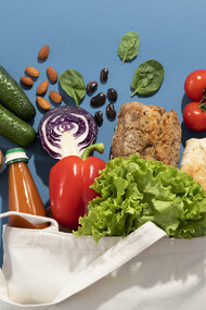 Una borsa della spesa in tela piena di prodotti freschi come verdure, frutta, pane e legumi