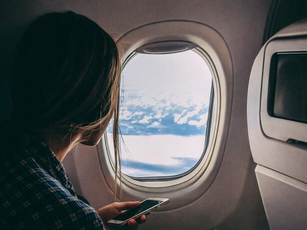 Person holding a smartphone while traveling on an airplane