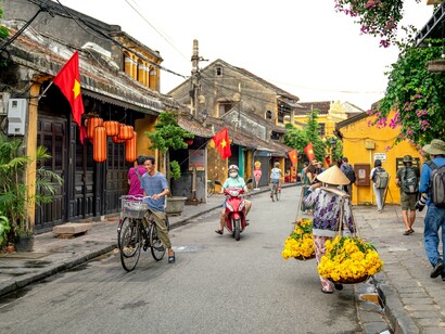 Pedestrians stroll through a lantern-lined street in Hoi An, Vietnam, surrounded by the town's well-preserved traditional architecture