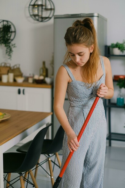 A woman mops the floor at home, appearing tired after hours of housework