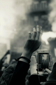 People filming an act of protest, demonstrating how young people use social media to spread awareness during times of conflict and war