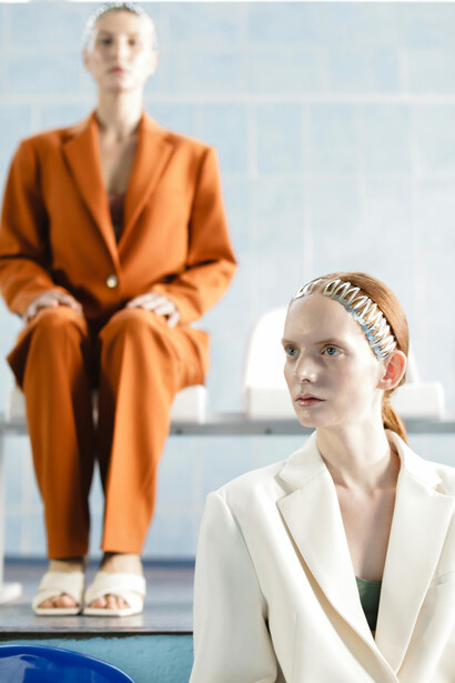 Embracing the oversized silhouette trend, models flaunt tailored suits and oversized blazers, accessorized with a lifebuoy for a unique and captivating visual contrast