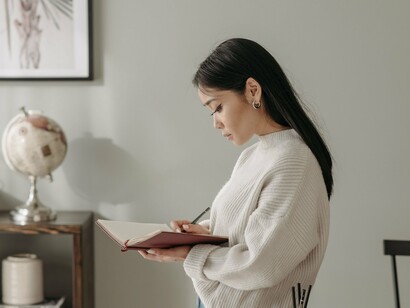 A woman thoughtfully writing in a journal, reflecting the healing power of expressing emotions left unsaid