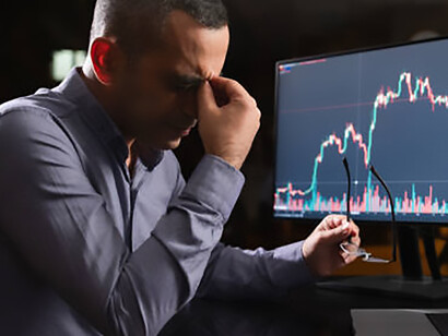 Exhausted man monitoring stock market exchange on laptop computer late at night