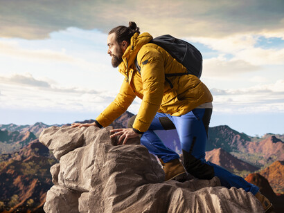 A lone traveler stands at the summit of a mountain, gazing at the surrounding peaks