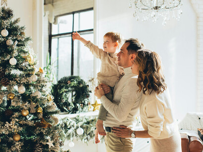 A happy family gathered on a rug next to a traditionally decorated Christmas tree