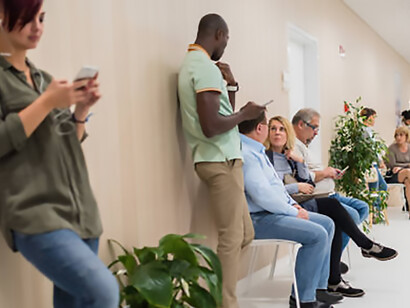 A busy, crowded hospital corridor where people wait both seated and standing