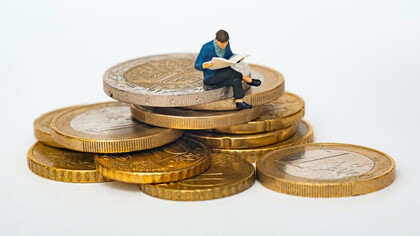 Sculpture of a person sitting on coins and thinking deeply