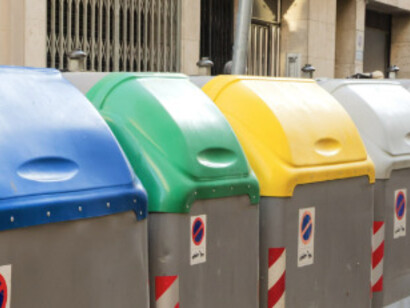 Intento echar la basura en los contenedores y encuentro carteles pegados anunciando "cada bolsa en su color" y "de 20h. a 23h." Vuelvo atrás con las 3 bolsas en ambas manos. Contenedores de residuos, Barcelona, España