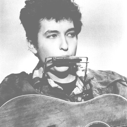 Bob Dylan playing two of his signature instruments: the acoustic guitar and the harmonica