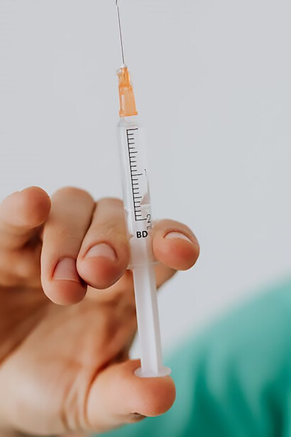 Amidst a backdrop of healthcare dedication, a doctor's hand firmly clutches a vial of life-saving vaccine, illustrating the critical role of medical professionals in promoting community health