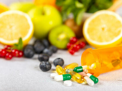 A variety of vitamin tablets arranged on a textured background, complemented by fresh and vibrant fruits, symbolizing the connection between multivitamins and healthy nutrition