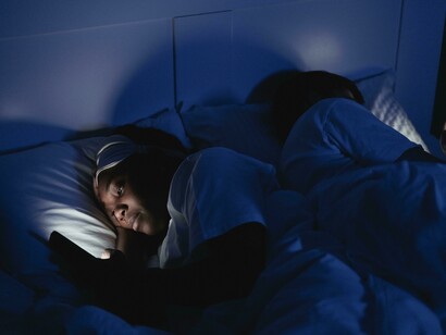 A woman lying on a bed uses her mobile phone