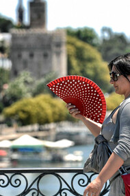 Combatiendo el calor con un abanico en el Puente de Triana, Sevilla