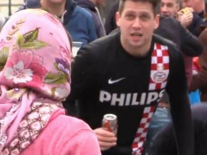 Un aficionado del PSV Eindhoven se burla de una mujer que pide limosna en la Plaza Mayor de Madrid