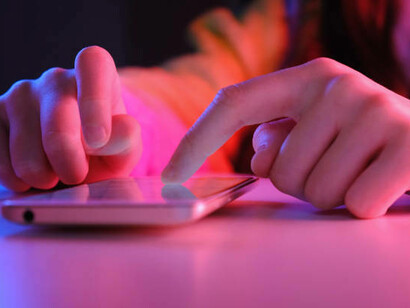 A woman reading news on her cell phone, participating in online activism by sharing political memes and viral content
